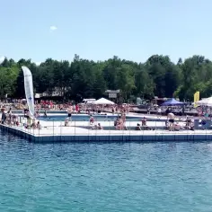 Tłum ludzi odpoczywa i kąpie się na pływającym basenie, prawdziwy polski Balaton w słoneczny dzień.