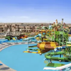 Kolorowy park wodny w stylu Neverland w Egipcie, z mnóstwem zjeżdżalni, basenów i budynków hotelowych w tle.