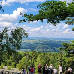 Widok na dolinę, gdzie w oddali wije się rzeka Słupia. Grupa turystów podziwia krajobraz z punktu widokowego.