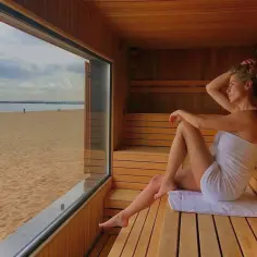 Kobieta w saunie z widokiem na plażę. Cieszy się relaksem, jak prawdziwi naturyści.