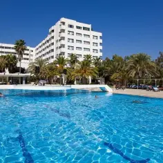 Słoneczny dzień w **sural garden Turcja**. Duży basen z błękitną wodą, palmy i biały hotel tworzą wakacyjny klimat.