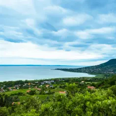 Malowniczy widok na Balaton, idealne miejsce na wczasy. W oddali widać wzgórza i zabudowania.