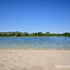 Piękny, słoneczny dzień nad jeziorem gołuchowskim. Piaszczysta plaża i spokojna tafla wody zapraszają do wypoczynku.