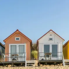 Kolorowe domki na plaży tworzą spokojne miejsce nad morzem. Idealne na wakacje.