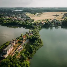 Widok na największe miasto Mazur, z zabudowaniami nad jeziorem i starymi budynkami na półwyspie.
