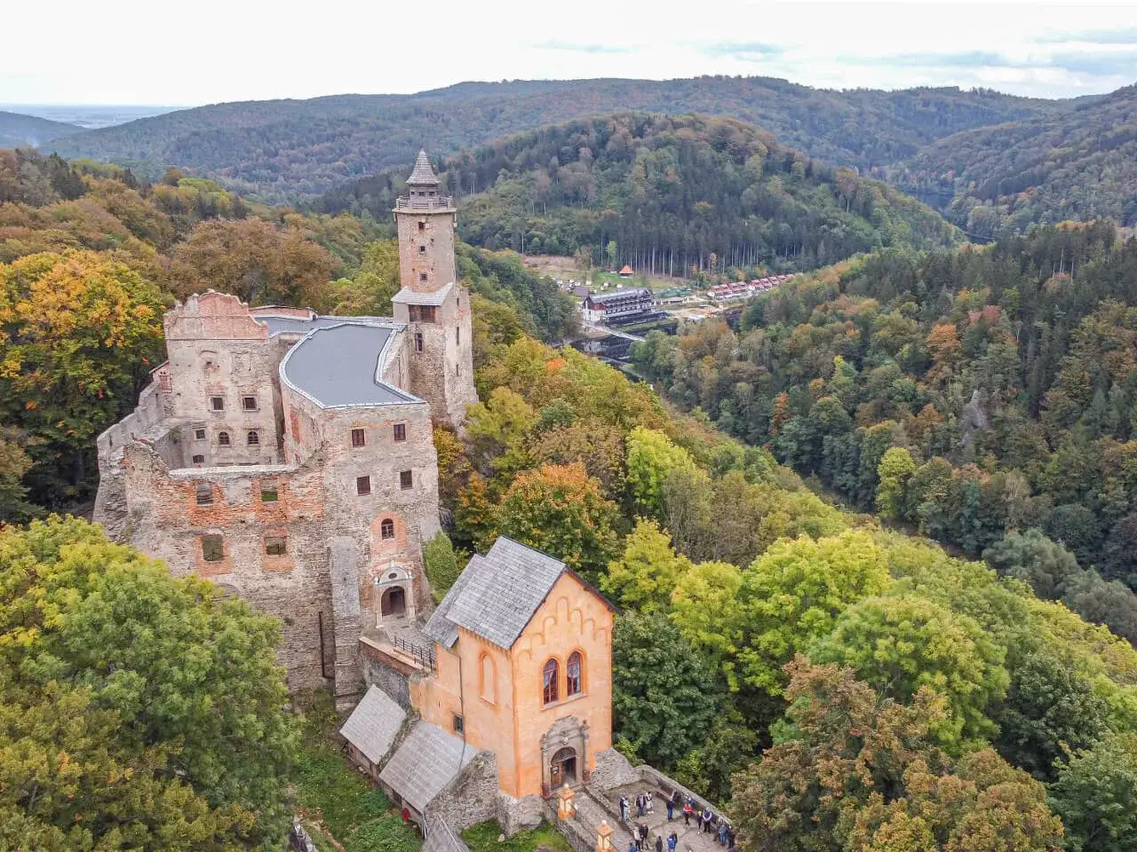 Zamek Książ w jesiennej scenerii, idealne miejsce na weekend z Wrocławia. Malownicze wzgórza i kolorowe drzewa otaczają zabytkowe mury.