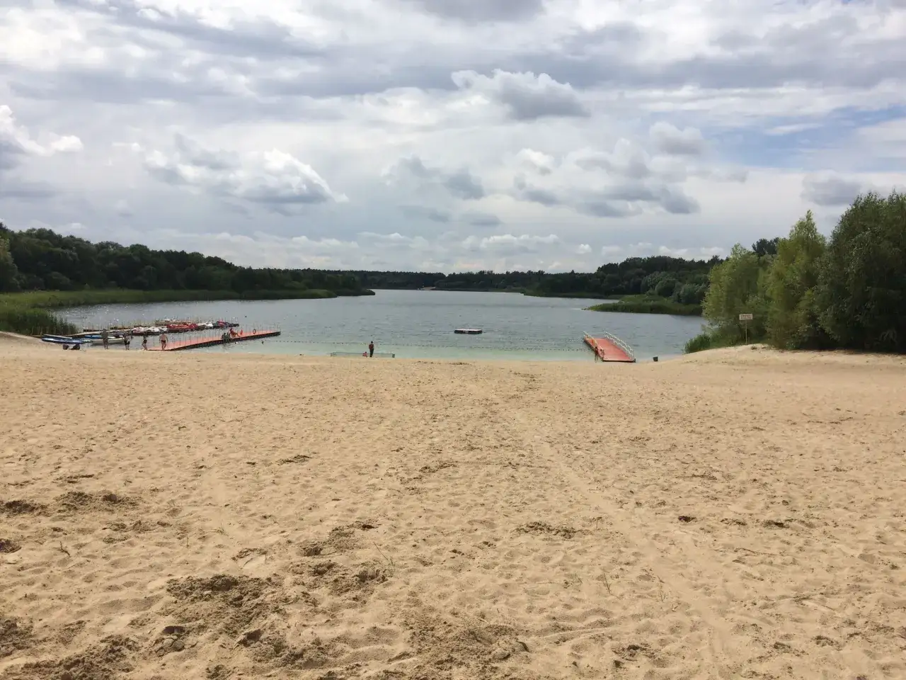 Plaża z pomostami i łódkami, idealne miejsce na letnie atrakcje.