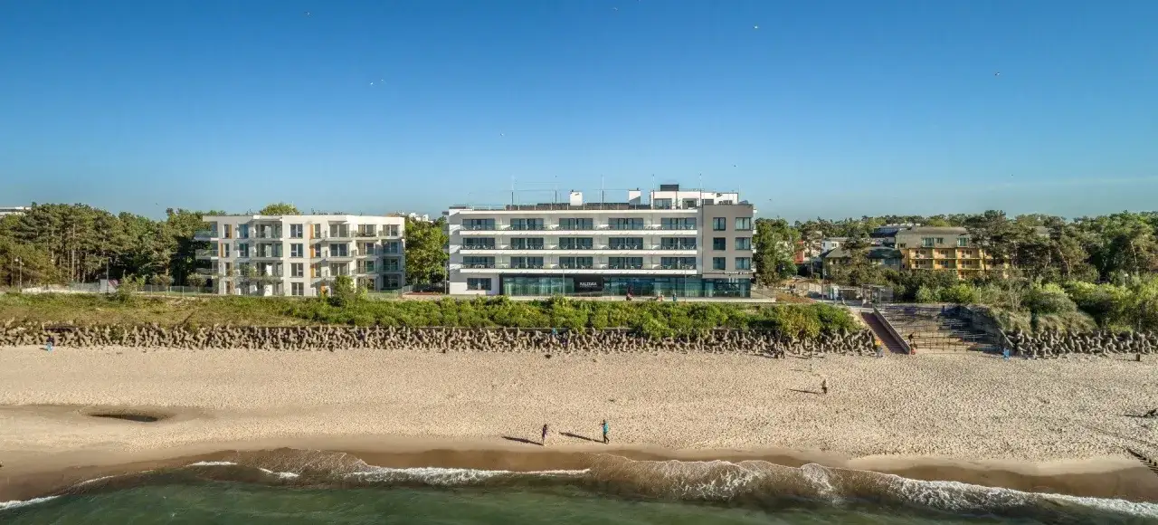 Nowoczesne budynki hotelowe nad piaszczystą plażą. Spokojne miejsce nad morzem, idealne na wypoczynek.