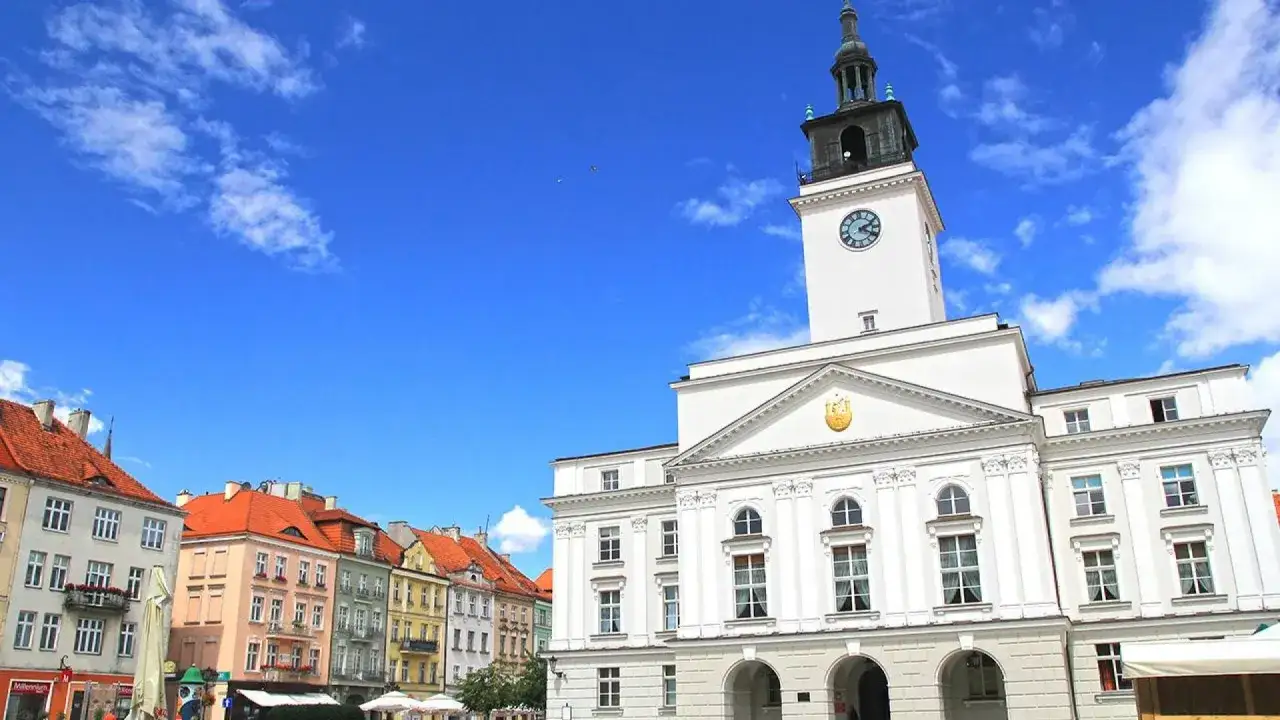 Rynek w Kalińcu z ratuszem i kolorowymi kamienicami pod błękitnym niebem.