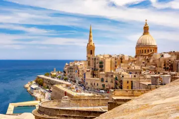 Malta last minute tanio! Widok na zabytkowe miasto z kopułą i wieżą, błękitne morze i basen. Idealne miejsce na wakacje.
