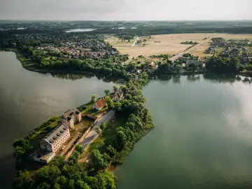 Widok na największe miasto Mazur, z zabudowaniami nad jeziorem i starymi budynkami na półwyspie.