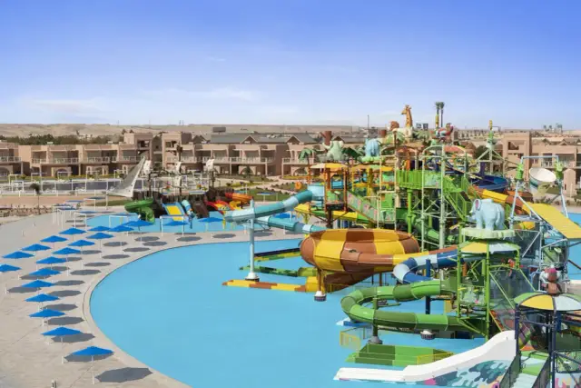 Kolorowy park wodny w stylu Neverland w Egipcie, z mnóstwem zjeżdżalni, basenów i budynków hotelowych w tle.