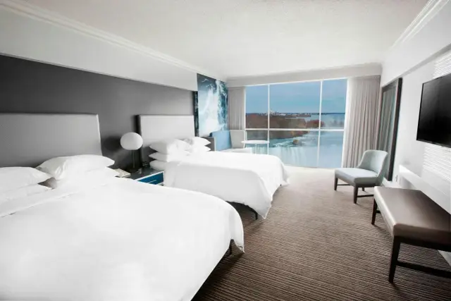 Pokój hotelowy z widokiem na wodospad Niagara. Dwa łóżka, wygodne fotele i okno z panoramą. Warto poznać wodospad Niagara informacje!