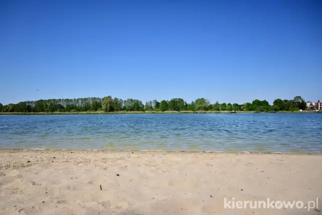 Piękny, słoneczny dzień nad jeziorem gołuchowskim. Piaszczysta plaża i spokojna tafla wody zapraszają do wypoczynku.